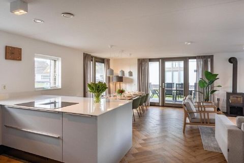 You have a view of the spacious terrace, which is accessible through the large glass patio doors. The dining area is connected to the spacious open kitchen with a cooking island, equipped with modern appliances. The bedroom has a sink.